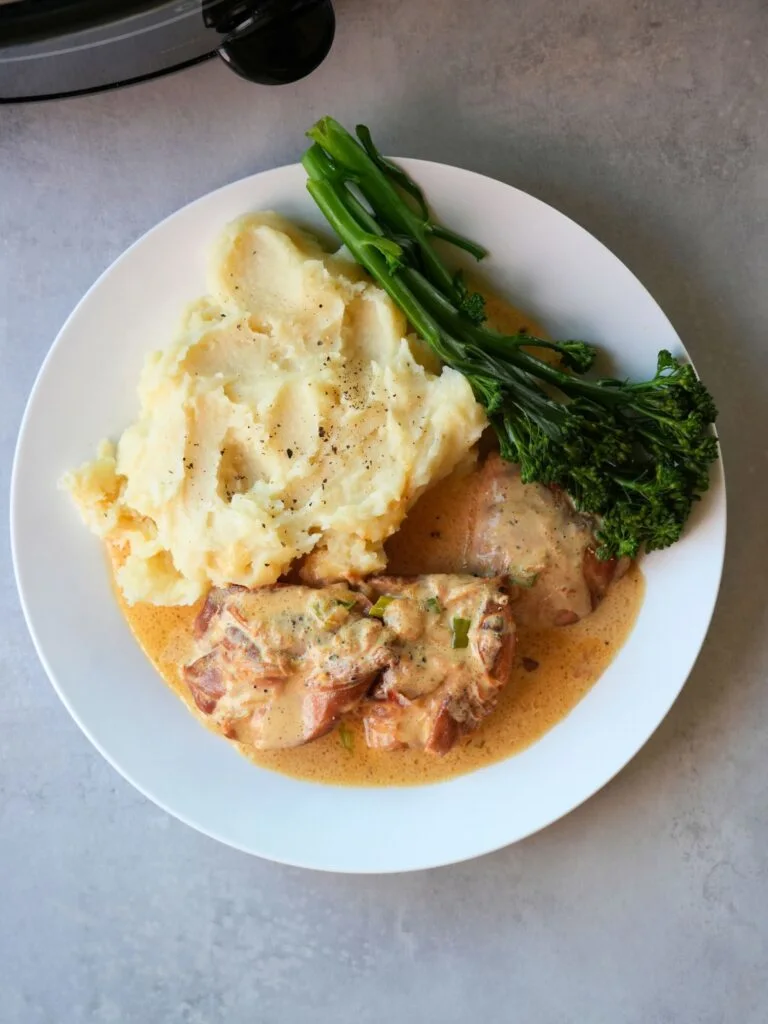 honey mustard chicken next to mashed potato and broccoli on a white plate next to a slow cooker