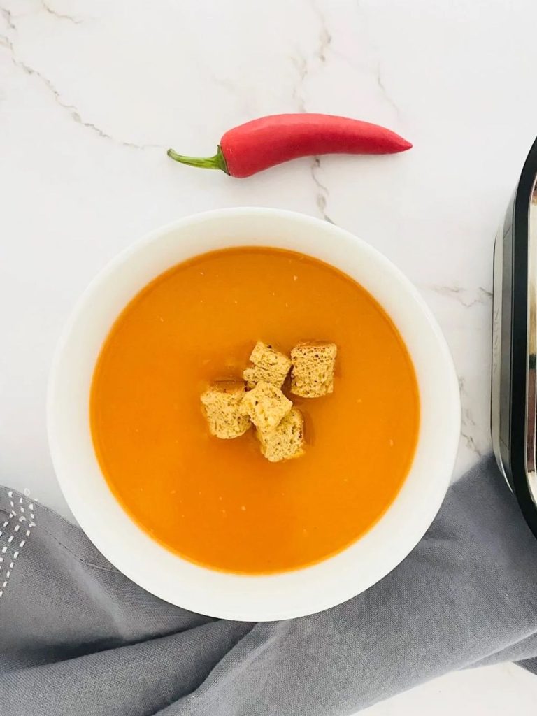 red pepper chilli soup next to a Ninja soup maker and fresh red chilli