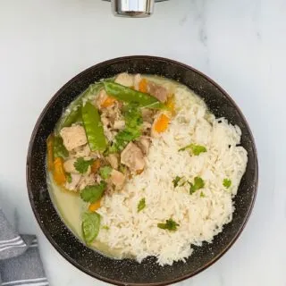 thai green curry with rice in a bowl next to a Ninja Foodi 15 in 1 multicooker
