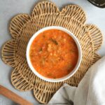 vegetable and lentil soup in a bowl on a placemat with a wooden spoon and cloth next to the ninja soup maker and blender