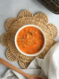 vegetable and lentil soup in a bowl on a placemat with a wooden spoon and cloth next to the ninja soup maker and blender