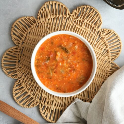 vegetable and lentil soup in a bowl on a placemat with a wooden spoon and cloth next to the ninja soup maker and blender