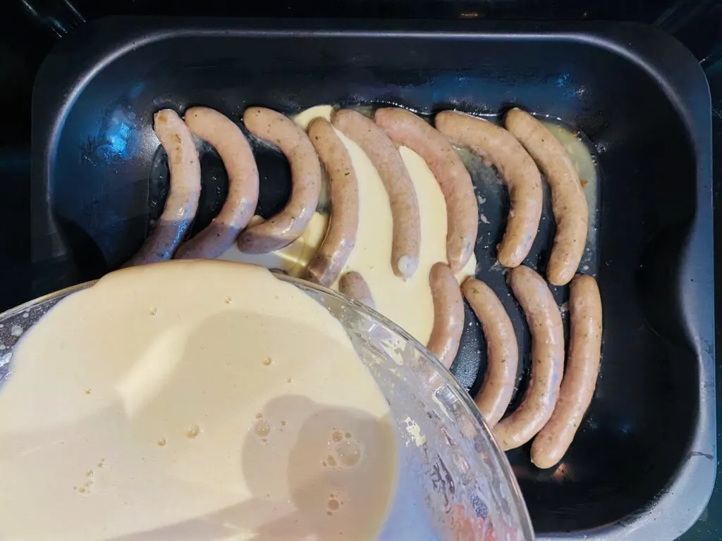 adding batter to sausages for toad in the hole