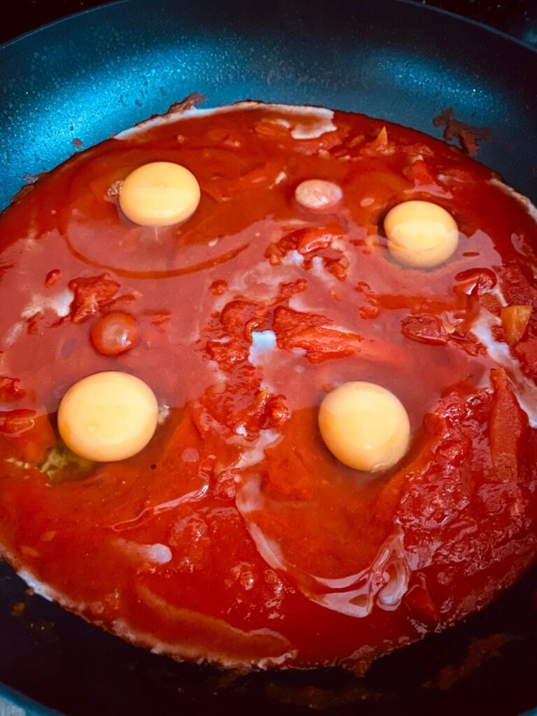 adding eggs to shakshuka