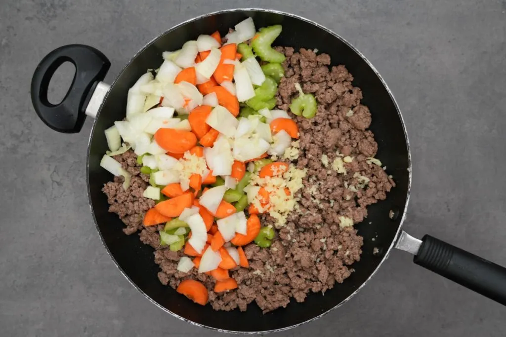 adding onions and garlic to mince for lasagne