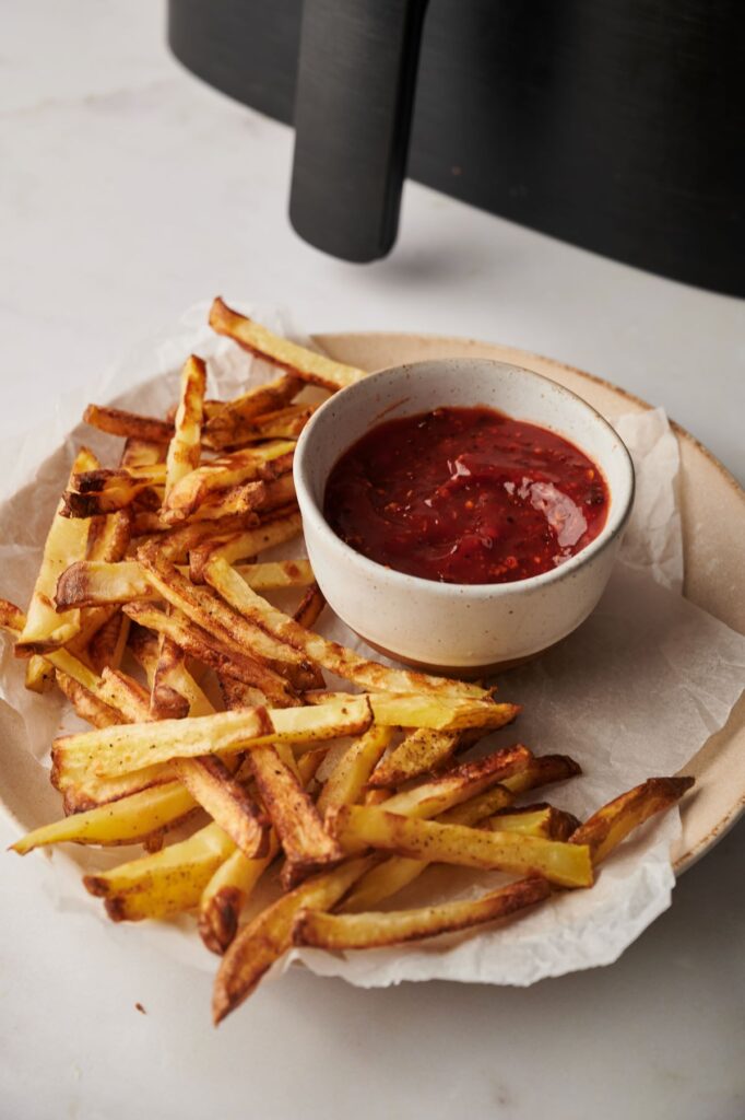 chips next to tomato ketchup on a plate and air fryer