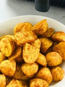 Bombay inspired new potatoes in a bowl in front of an air fryer