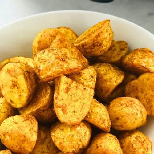 Bombay inspired new potatoes in a bowl in front of an air fryer