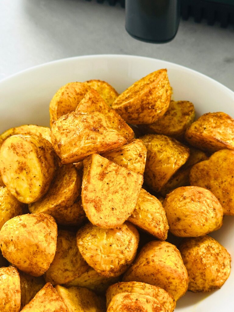 Bombay inspired new potatoes in a bowl in front of an air fryer