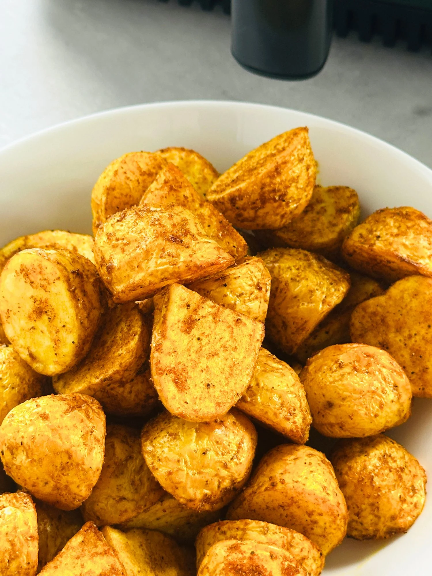 Bombay inspired new potatoes in a bowl in front of an air fryer