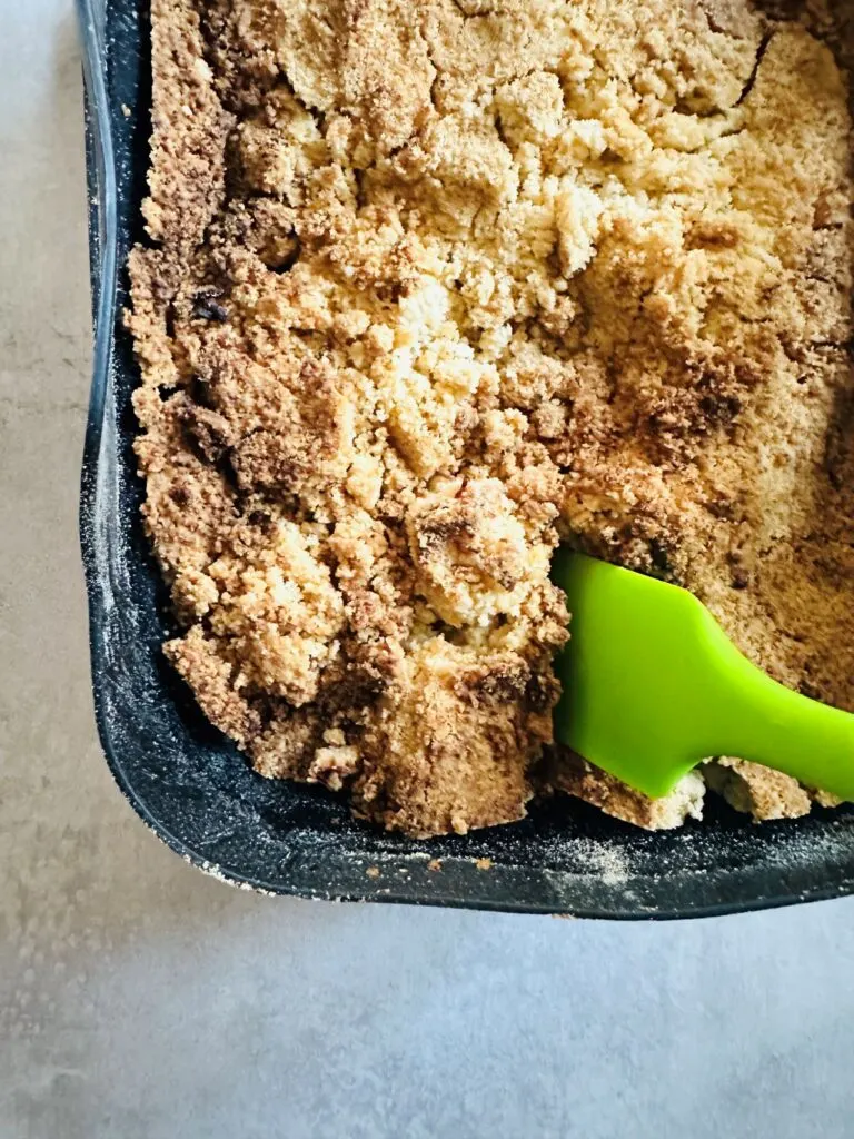green silicone spatula cutting up a cooked apple crumble in a silicone air fryer basket