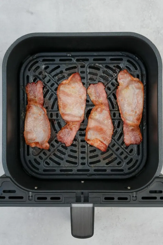 cooked bacon rashers in an air fryer basket