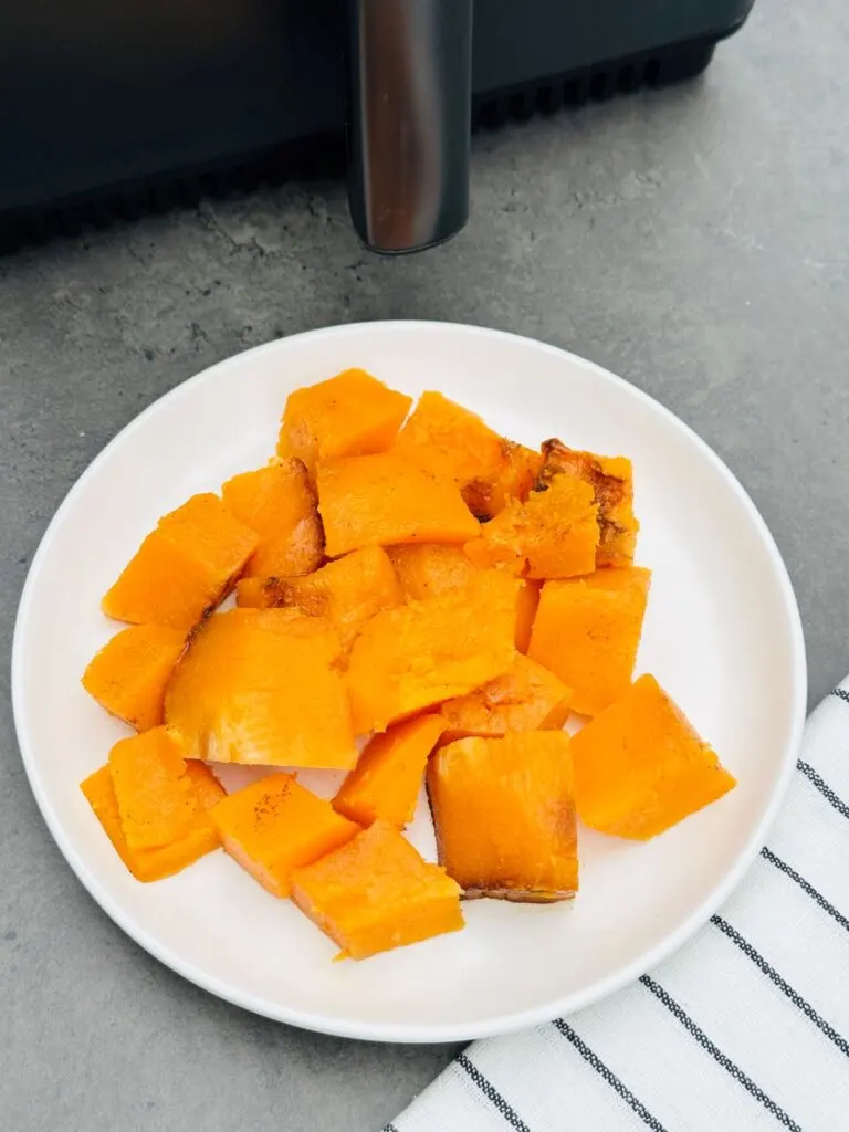 chopped butternut squash next to air fryer