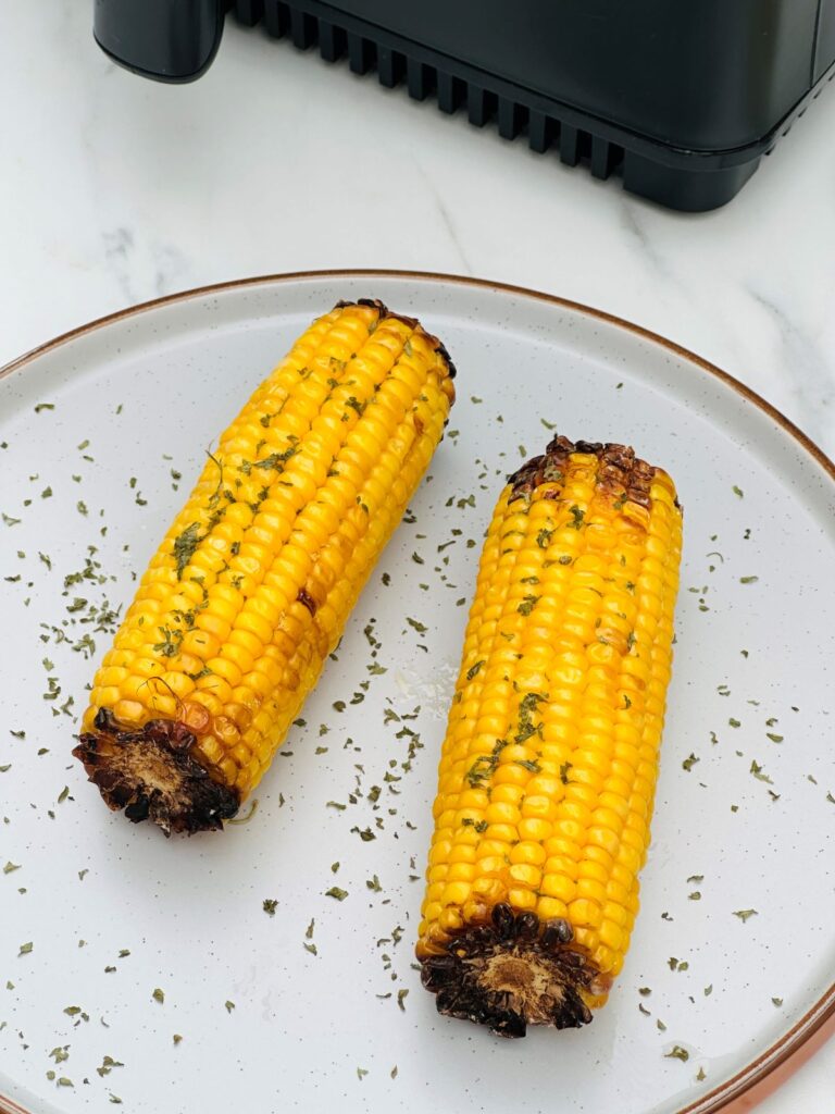 corn on the cob next to an air fryer