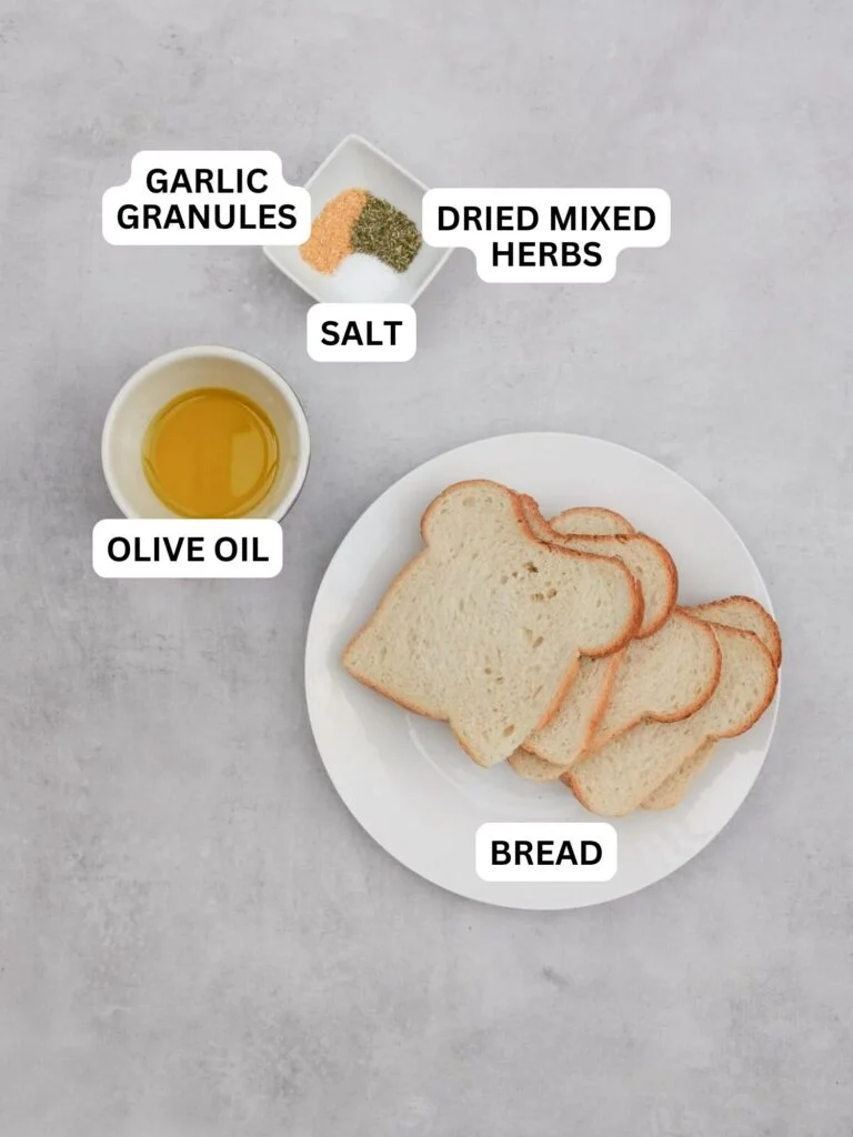 Ingredients laid out and labelled for croutons: Garlic Granules, Dried mixed herbs, salt, olive oil and 5 slices of bread