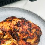 honey mustard chicken thighs on a plate next to an air fryer