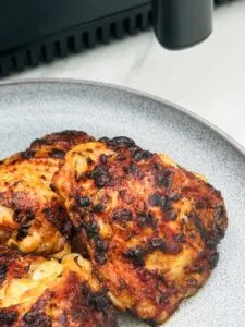 honey mustard chicken thighs on a plate next to an air fryer