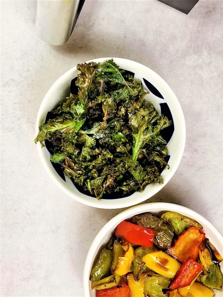 air fryer kale chips and air fryer roasted peppers in bowls next to a Ninja Dual air fryer