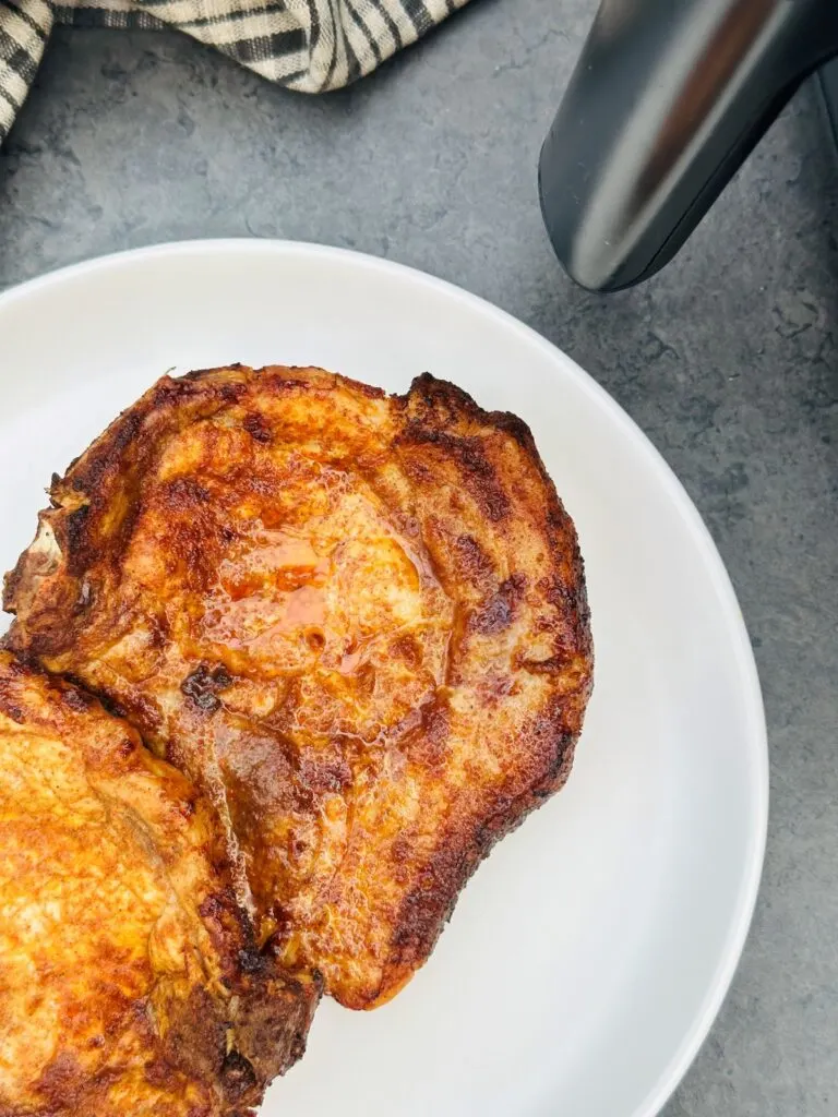 paprika pork chops on a plate next to an air fryer