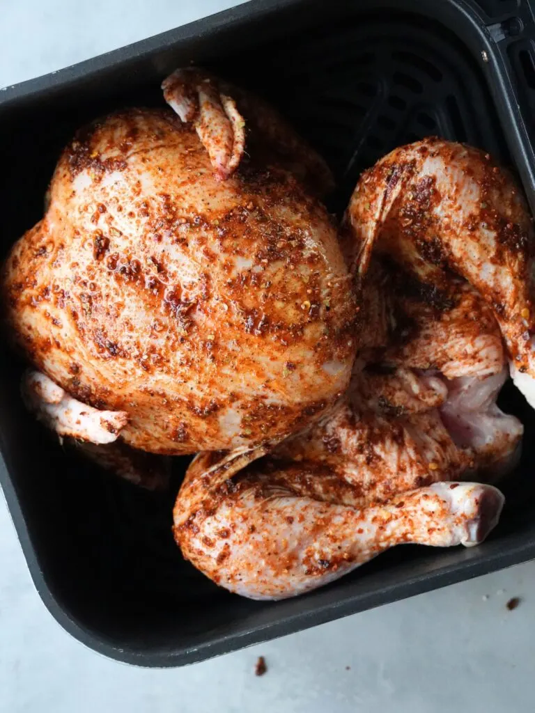 whole chicken in an air fryer with peri peri paste over it