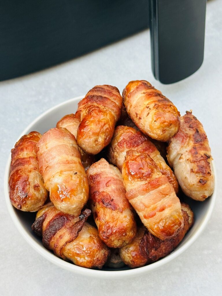 pigs in blankets in bowl next to air fryer