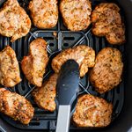 pork medallions in the air fryer with tongs picking one up