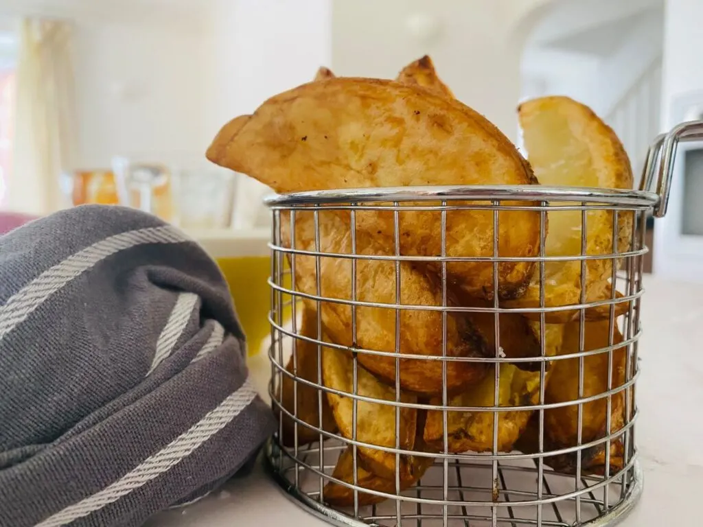 air fryer potato wedges placed in a basket for serving