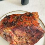 air fryer roasted half leg of lamb next to an air fryer basket