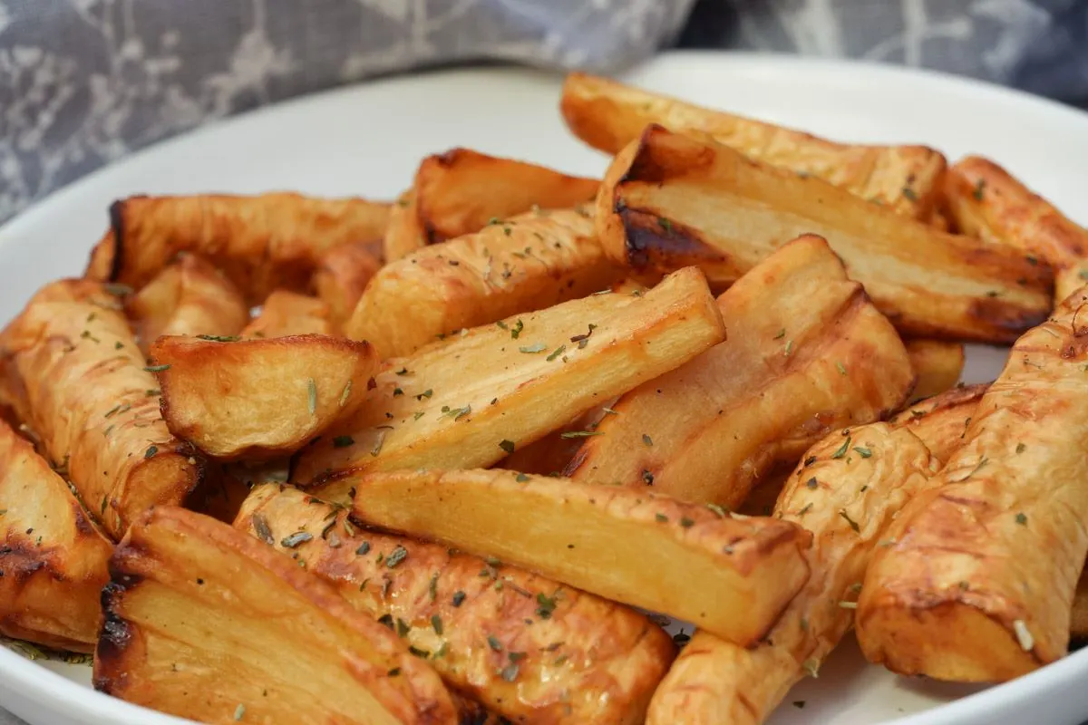 roasted parsnips on a plate with dried herbs sprinkled on top