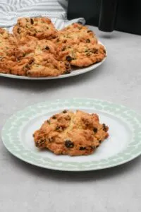 air fryer rock cake on plate in front of plate of more rock cakes with an air fryer in the background