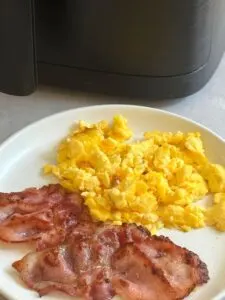 air fryer scrambled eggs with bacon on plate
