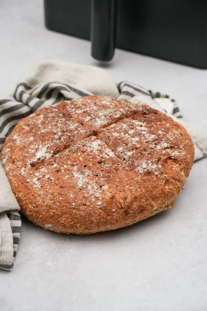 just baked soda bread resting on tea towel next to air fryer