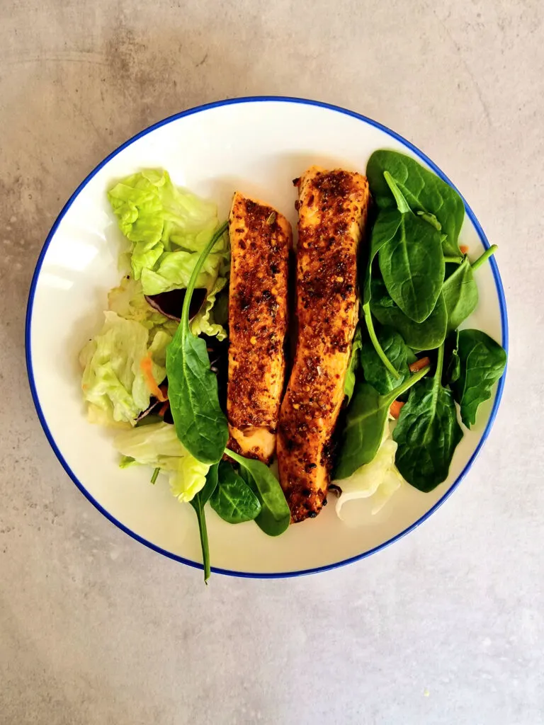 air fried salmon on a plate with green salad