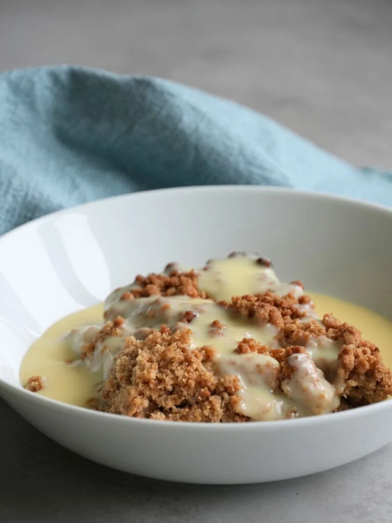 apple crumble in bowl with fresh cutard on top