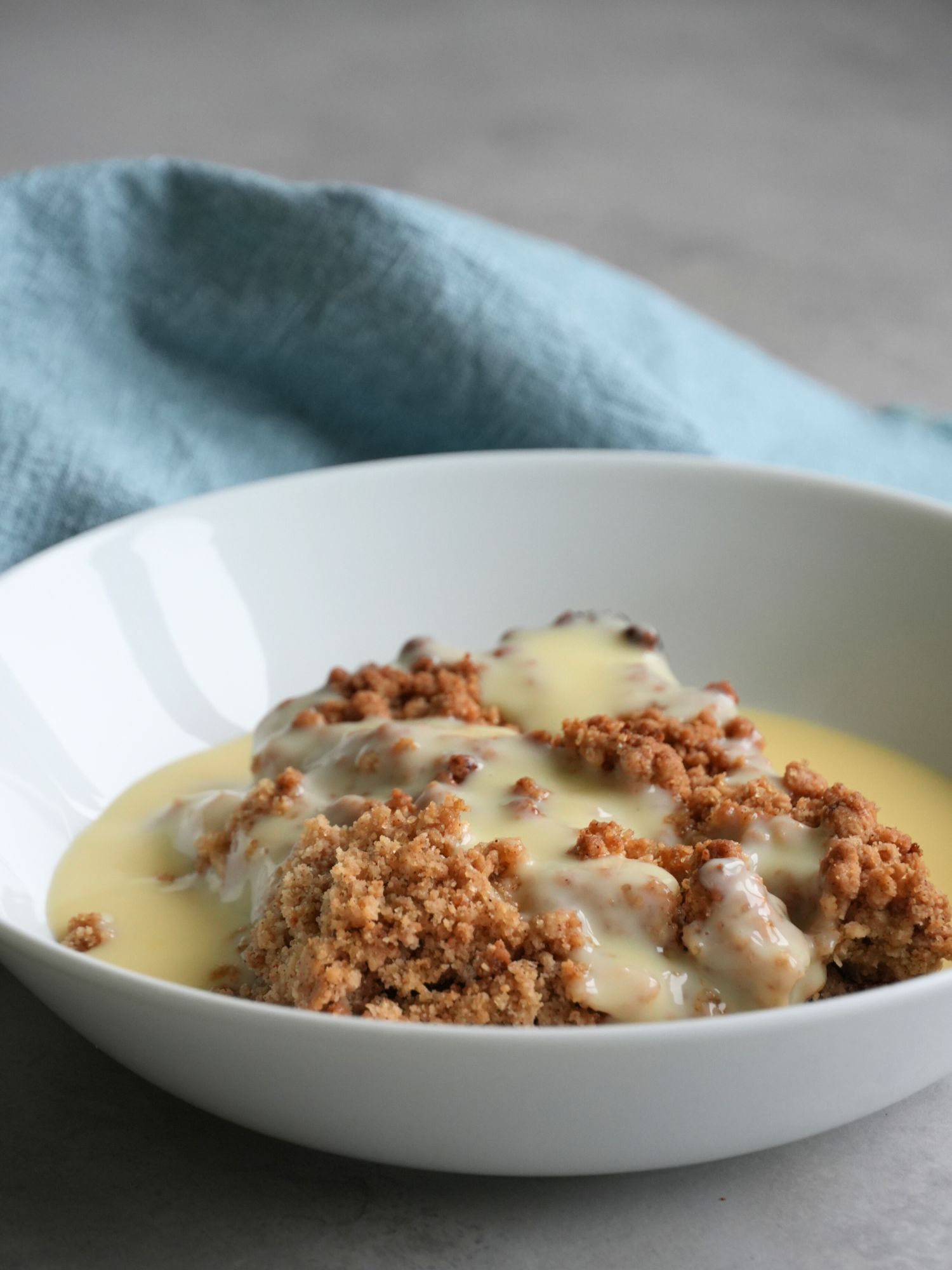 apple crumble in bowl with fresh custard on top