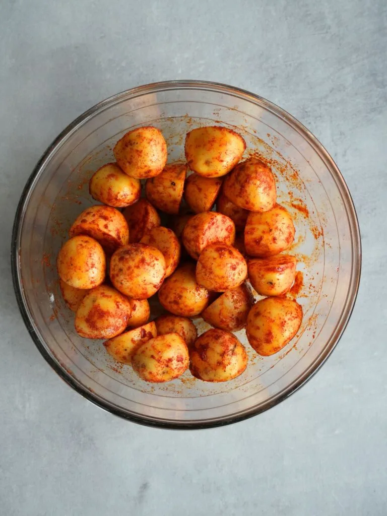 glass bowl with halved baby potatoes that have been seasoned with smoked paprika and garlic powder, uncooked