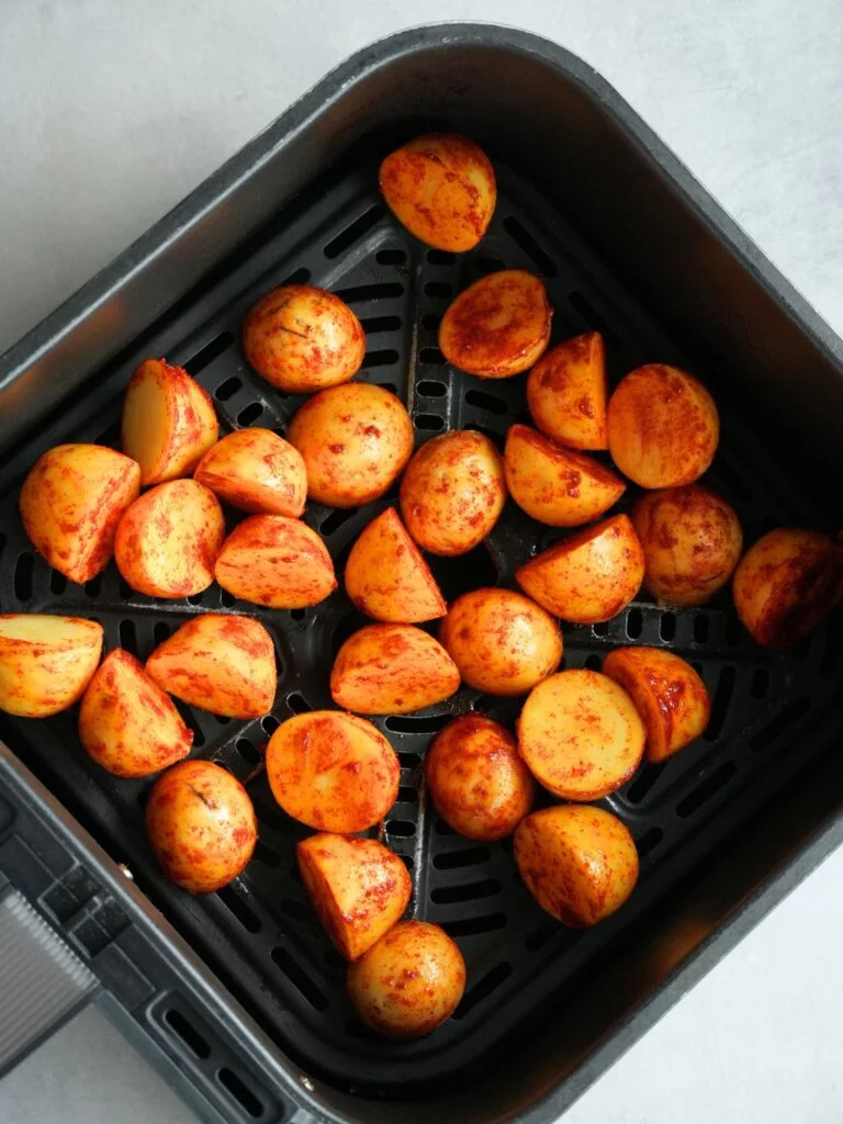 baby potatoes, seasoned, in air fryer basket before being cooked