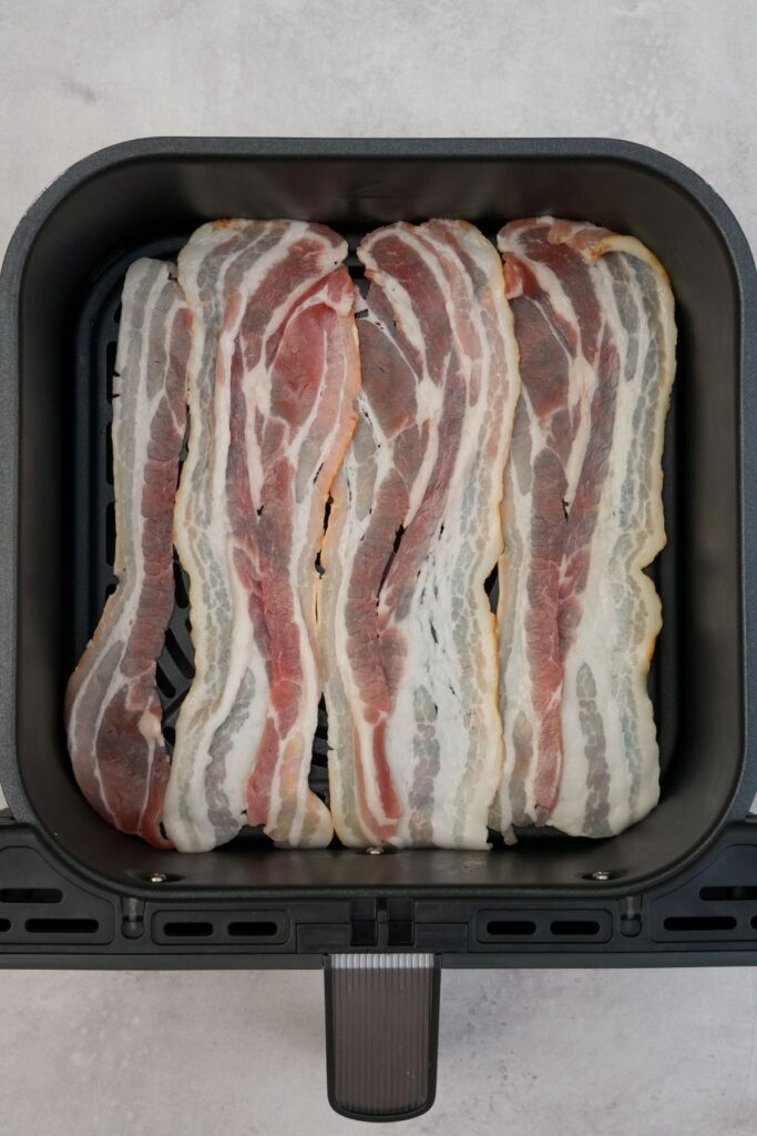 four rashers of bacon in an air fryer basket