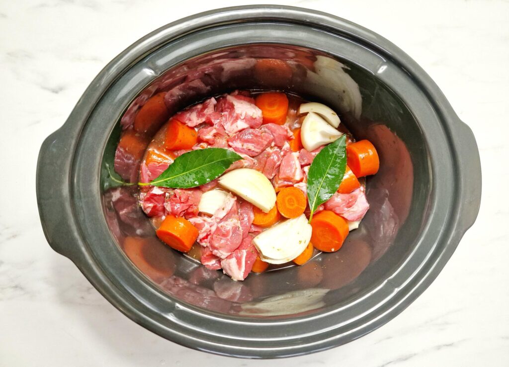 raw lamb stew ingredients in slow cooker