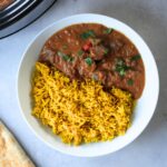 beef curry next to pilau rice and naan bread and slow cooker