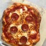 cooked pizza with pepperoni on a pizza peel
