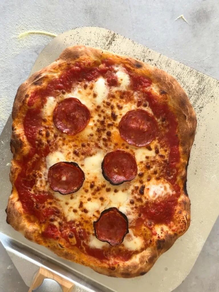 cooked pizza with pepperoni on a pizza peel