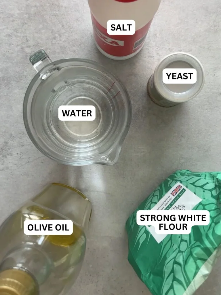 ingredients laid out for bread maker pizza dough - water, salt, yeast, olive oil and strong white flour