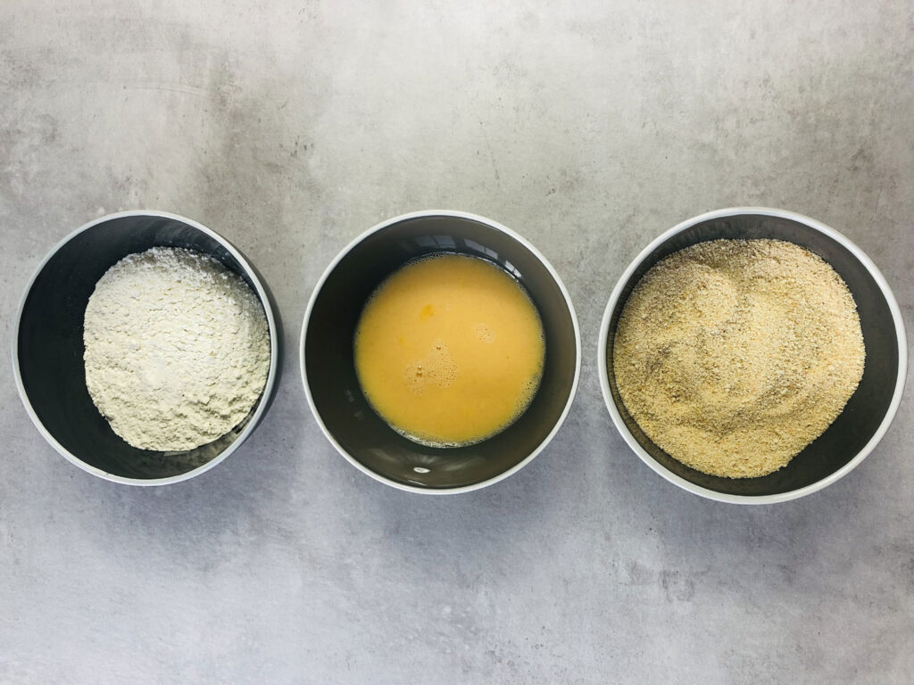 breading station for chicken nuggets. Three bowls in a line; flour, egg and breadcrumbs 