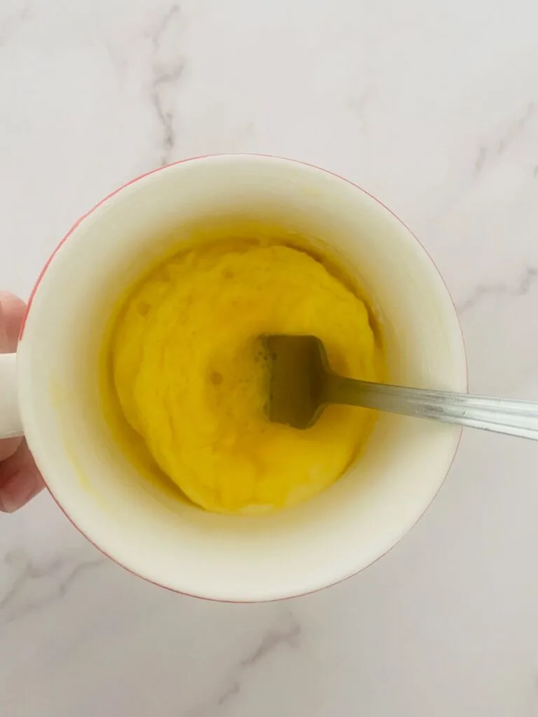 scrambled egg in mug from microwave with fork to fluff it up