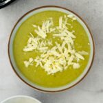 broccoli and cheddar soup in a bowl next to a ninja soup maker