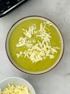 broccoli and cheddar soup in a bowl next to a ninja soup maker