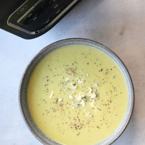 broccoli and stilton soup in a bowl with crumbled stilton on top next to a Ninja soup maker