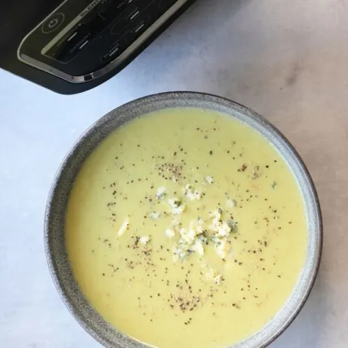 broccoli and stilton soup in a bowl with crumbled stilton on top next to a Ninja soup maker