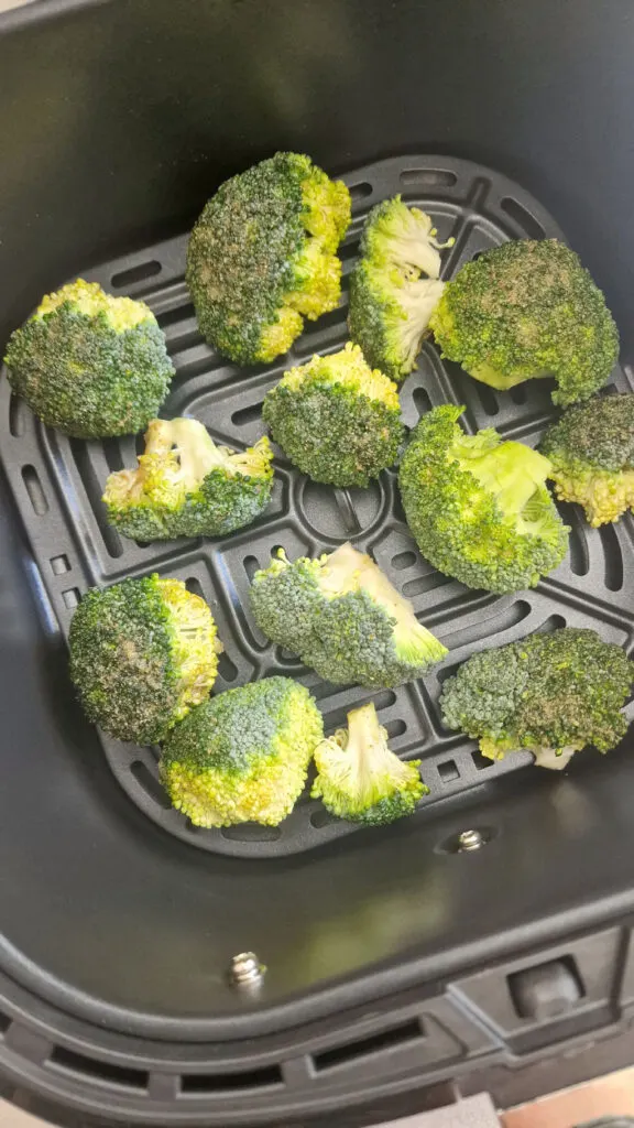 seasoned broccoli in air fryer basket 